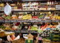 Variety of fruits and vegetables displayed on shelves in a grocery store.
