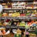 Variety of fruits and vegetables displayed on shelves in a grocery store.