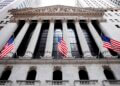 Facade of the New York Stock Exchange building with American flags and columns.