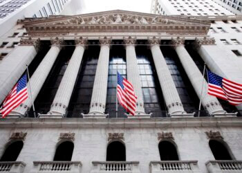 Facade of the New York Stock Exchange building with American flags and columns.