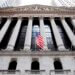 Facade of the New York Stock Exchange building with American flags and columns.