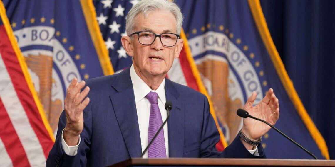 Jerome Powell, Chair of the Federal Reserve, speaking at a press conference with flags in the background.