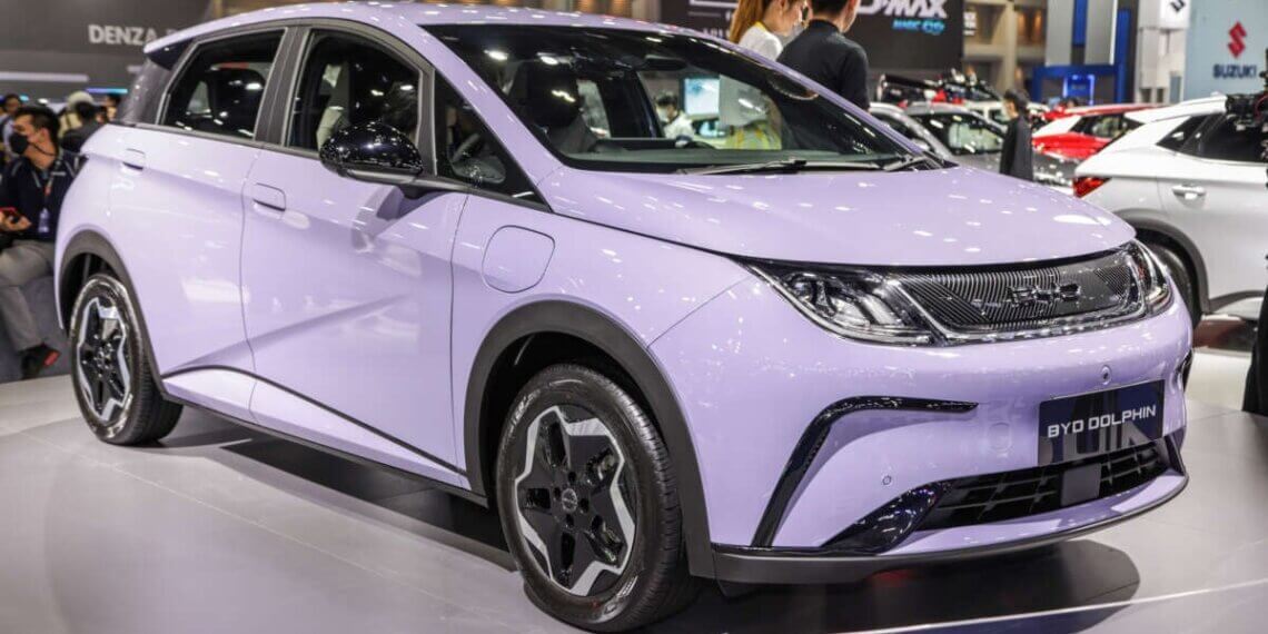A lavender BYD Dolphin electric car displayed at an auto show with a modern design.