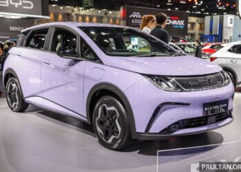 A lavender BYD Dolphin electric car displayed at an auto show with a modern design.