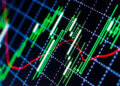 Close-up of a stock market chart displaying green and red candlestick indicators on a grid background.