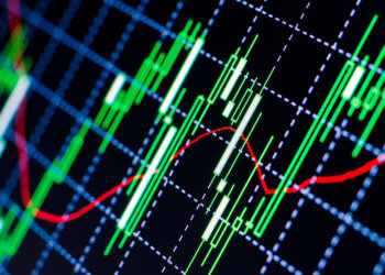 Close-up of a stock market chart displaying green and red candlestick indicators on a grid background.
