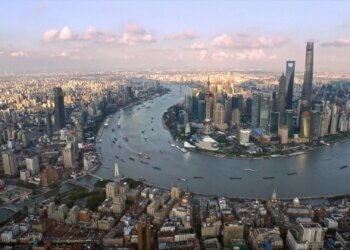 Aerial view of Shanghai showcasing the skyline and the winding Huangpu River with buildings and boats.
