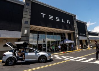 Tesla Model X with open falcon wing doors parked outside a Tesla service center.