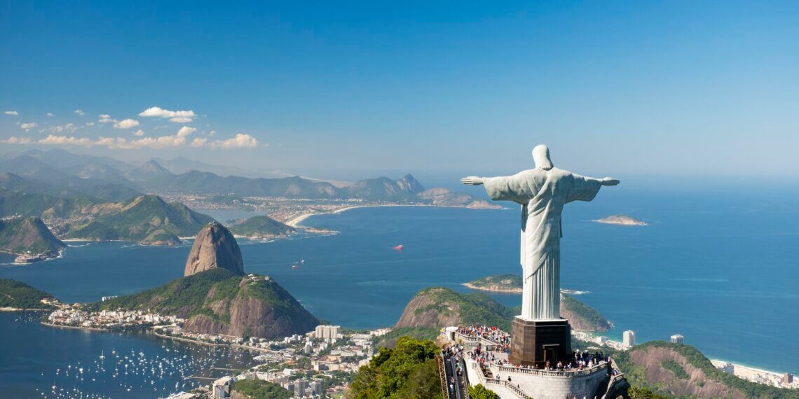 Christ the Redeemer statue with arms outstretched, overlooking Rio de Janeiro and the ocean.