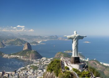 Christ the Redeemer statue with arms outstretched, overlooking Rio de Janeiro and the ocean.