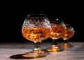 Three crystal glasses filled with amber cognac on a dark background.