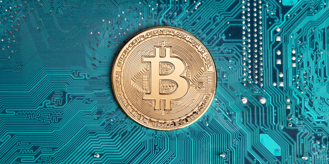 A gold Bitcoin coin placed on a blue circuit board with intricate patterns.