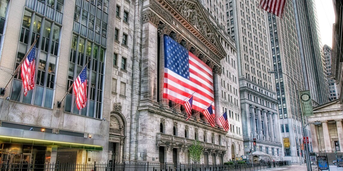 Facade of the New York Stock Exchange featuring a large American flag and multiple smaller flags.