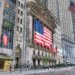 Facade of the New York Stock Exchange featuring a large American flag and multiple smaller flags.