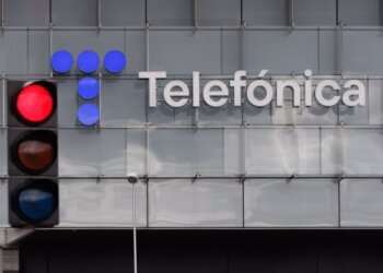 Red traffic light positioned in front of the Telefónica building with a logo.