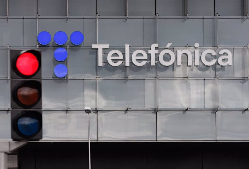 Red traffic light positioned in front of the Telefónica building with a logo.