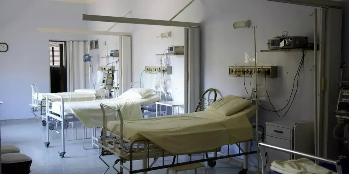 Interior of a hospital room featuring multiple empty hospital beds with medical equipment.