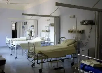 Interior of a hospital room featuring multiple empty hospital beds with medical equipment.