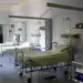 Interior of a hospital room featuring multiple empty hospital beds with medical equipment.