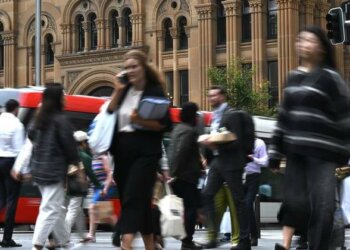 Pedestrians crossing a busy city intersection with blurred motion and vehicles in the background.