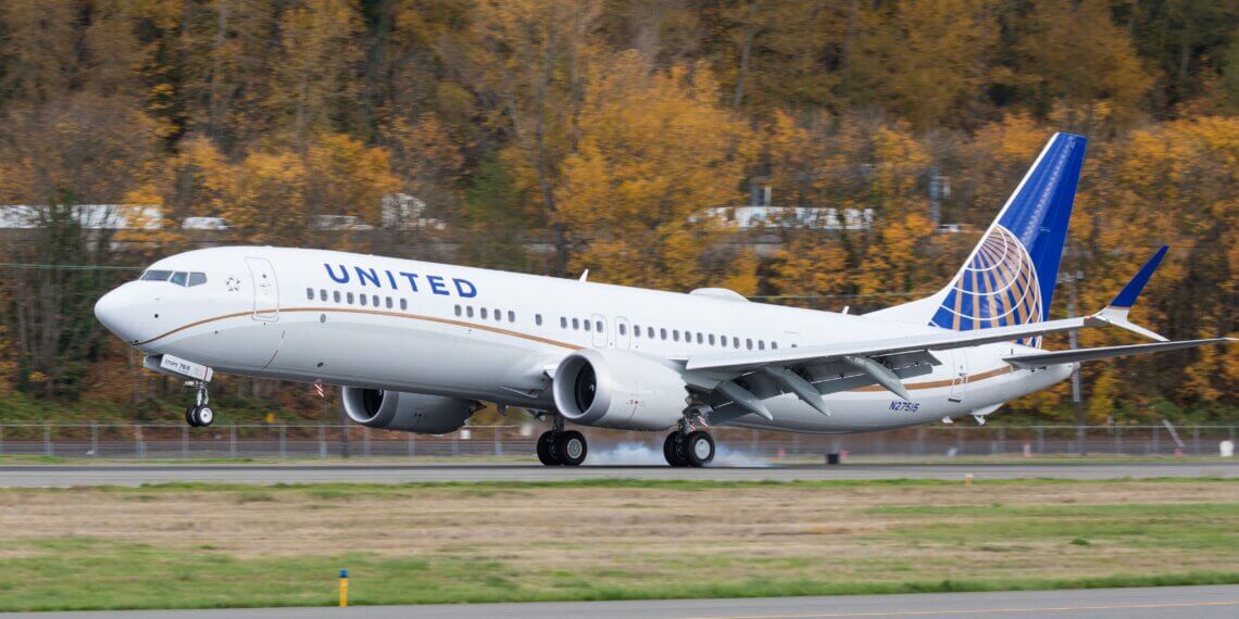 United Airlines Boeing 737 airplane taking off on a runway with autumn trees in the background.
