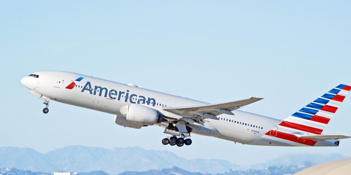 American Airlines Boeing 777 aircraft taking off with a clear sky in the background.