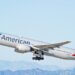 American Airlines Boeing 777 aircraft taking off with a clear sky in the background.