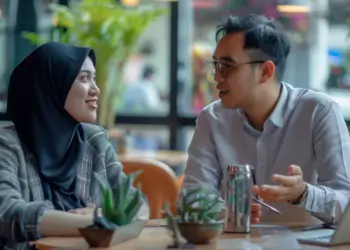 A man and a woman sitting at a table, engaged in conversation in a cafe setting.