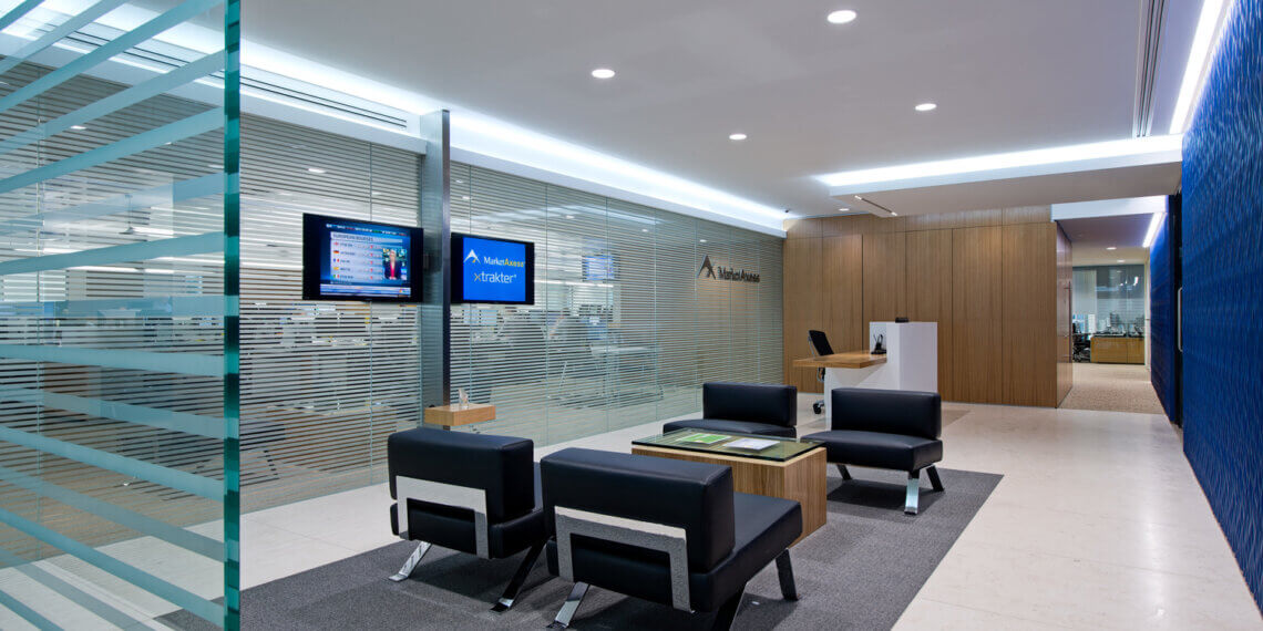 Contemporary reception area featuring black chairs, a wooden table, and a television screen on the wall.