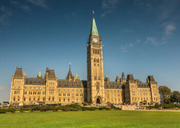 The Centre Block of Parliament Hill in Ottawa, Ontario, featuring a clock tower and Gothic architectural style.