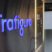 Illuminated sign displaying the name 'Trafigura' in a modern office setting.