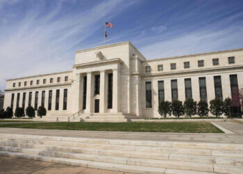 The Federal Reserve building in Washington, D.C. with a flag on top and steps leading to the entrance.