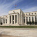 The Federal Reserve building in Washington, D.C. with a flag on top and steps leading to the entrance.
