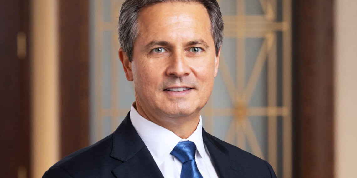 Portrait of a man in a suit and tie with a neutral expression in a professional setting.