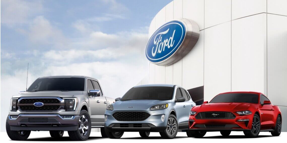 Three Ford vehicles displayed in front of a Ford logo on a building.