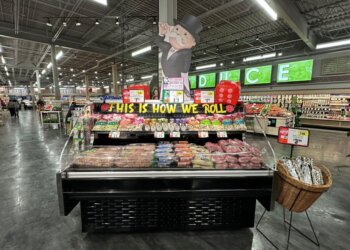Meat display case featuring various cuts of meat and a promotional sign in a grocery store.