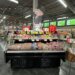 Meat display case featuring various cuts of meat and a promotional sign in a grocery store.