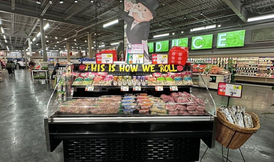 Meat display case featuring various cuts of meat and a promotional sign in a grocery store.